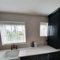 white Venetian blinds in stylish kitchen with farmhouse sink