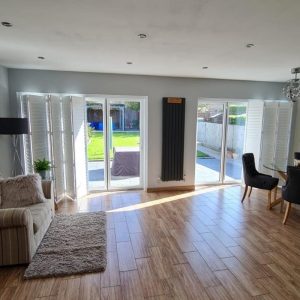 pushed open white tracked shutters in modern living room diner