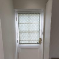 pale geometric Roman blinds on door glazing