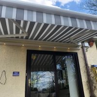 Tri-Striped Awning with lighting above entrance to property