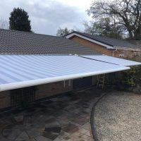 Striped awnings across roof of property overlooking stone garden area