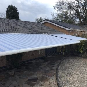 Striped awnings across roof of property overlooking stone garden area