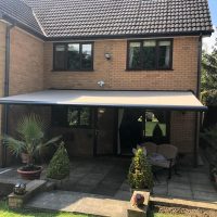grey electric awnings above sliding doors on house