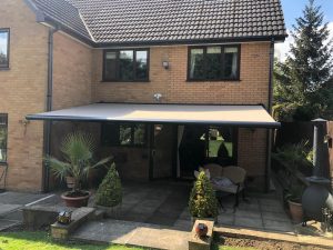 grey electric awnings above sliding doors on house
