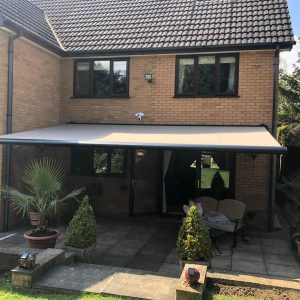 grey electric awnings above sliding doors on house