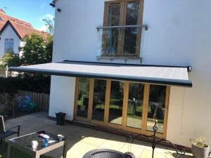 grey electric awnings above sliding doors on house
