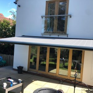 grey electric awnings above sliding doors on house